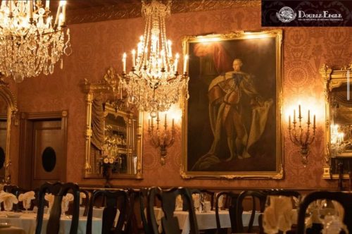 Elegant dining room with chandeliers, ornate decor, and a large portrait on the wall.