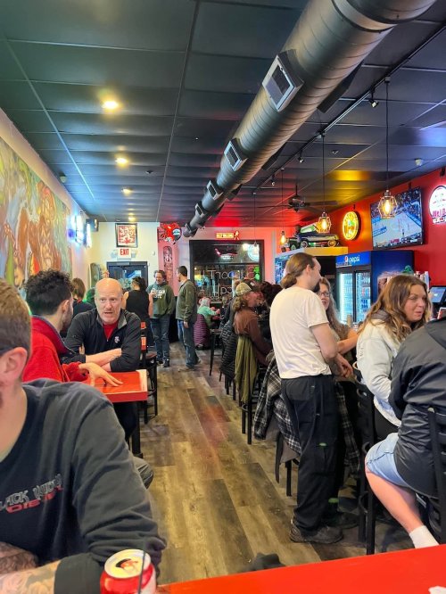 A busy restaurant interior with patrons seated at tables, colorful decor, and a lively atmosphere.