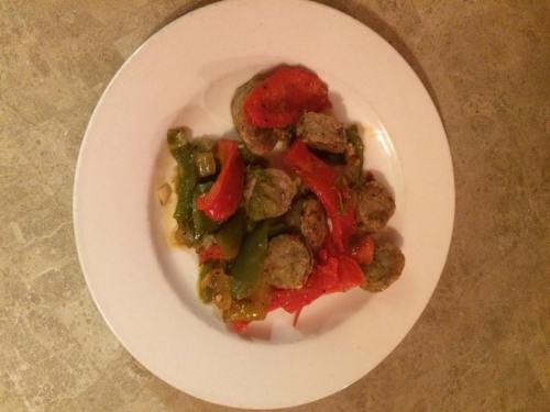 A plate of meatballs with sautéed green and red bell peppers on a textured surface.