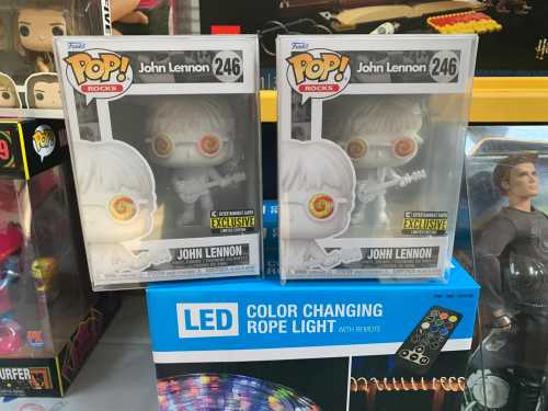 Two Funko Pop! figures of John Lennon in boxes, displayed on top of a color-changing LED rope light.