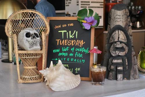 A bar display featuring a chalkboard sign for Tiki Tuesday, a skull, a tiki statue, and a cocktail with an umbrella.