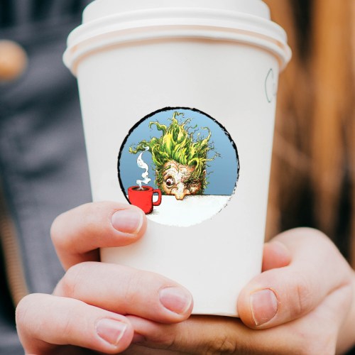 A person holds a coffee cup featuring a whimsical design of a creature with green hair peeking over a red mug.