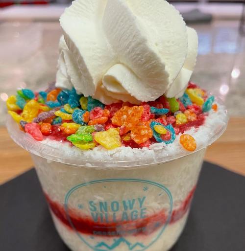 A dessert cup filled with fluffy white cream, colorful cereal, and a swirl of whipped cream on top.