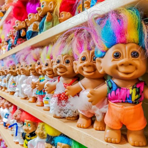 A colorful display of troll dolls with vibrant hair, lined up on a shelf.