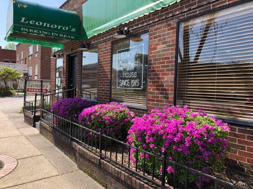 Exterior of Leonoro's restaurant with a green awning, brick facade, and vibrant purple flowers in front.