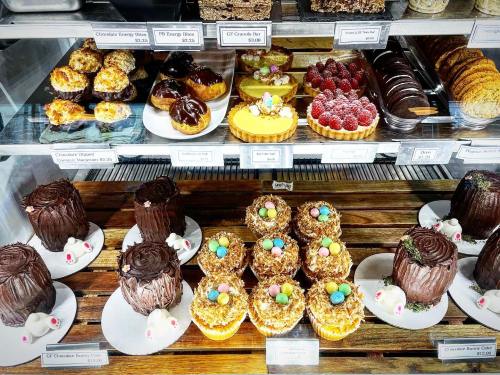 A display case filled with various pastries, including chocolate cakes, fruit tarts, and decorated cupcakes.