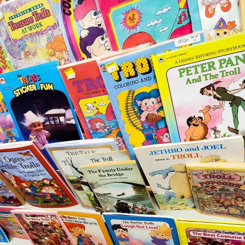 A colorful display of children's books featuring trolls, including activity books and storybooks.