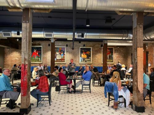 A bustling restaurant interior with patrons dining, exposed brick walls, and colorful artwork on display.