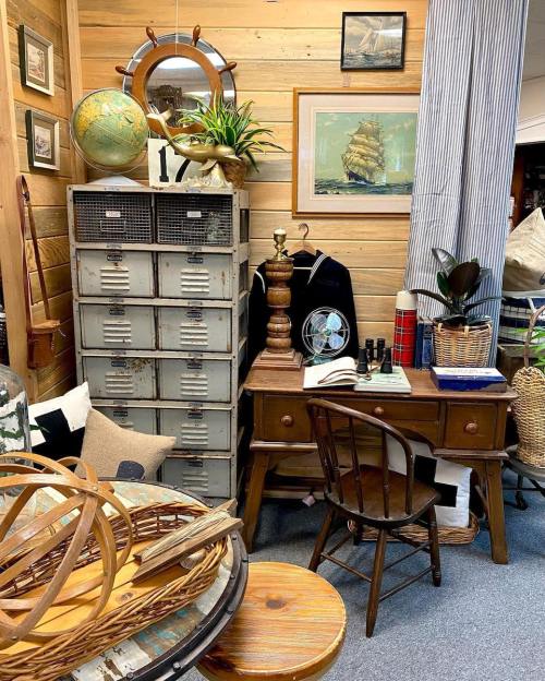 A cozy vintage corner featuring a wooden desk, chair, globe, and decorative items against a wooden wall.