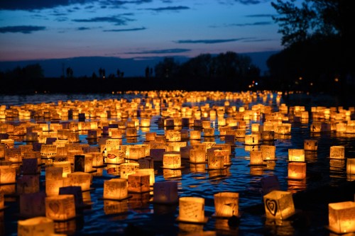 A serene river scene at dusk, filled with glowing lanterns floating on the water, creating a warm, magical atmosphere.