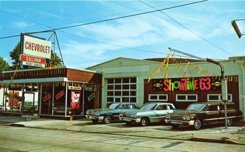 A vintage Chevrolet service station with colorful banners and classic cars parked outside, showcasing a retro atmosphere.