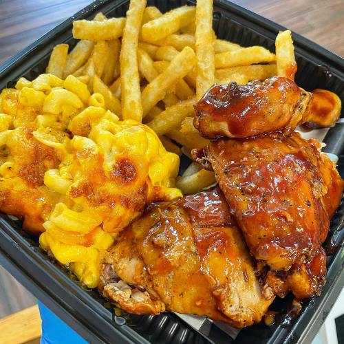A takeout container with BBQ chicken, macaroni and cheese, and French fries.