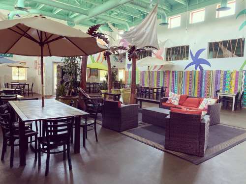 Brightly colored indoor dining area with umbrellas, plants, and cozy seating arrangements.