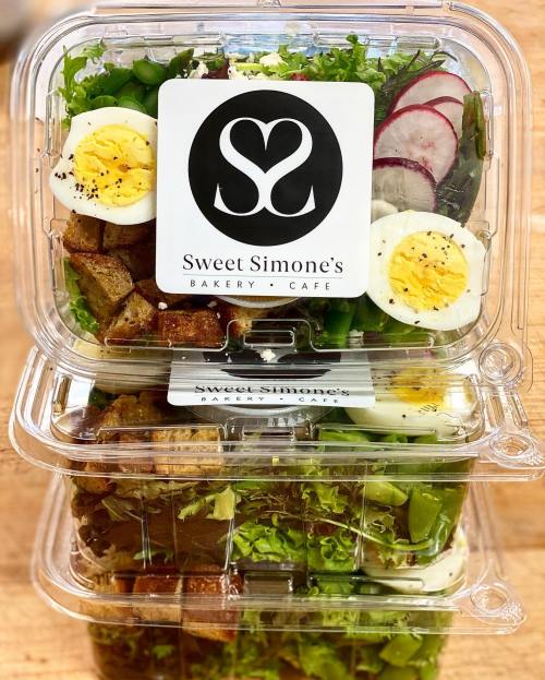 Three stacked containers of fresh salad with greens, sliced radishes, croutons, and halved boiled eggs, labeled "Sweet Simone's."