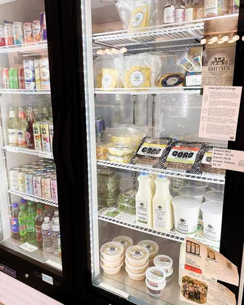 A refrigerator display filled with various drinks, snacks, and packaged foods, including milk and desserts.