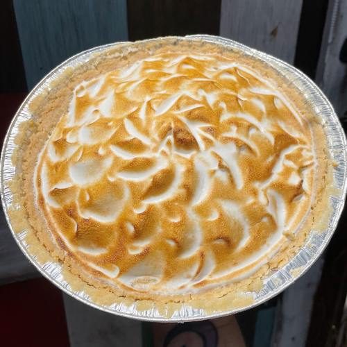 A golden-brown meringue pie in a silver pie dish, with a textured, swirled topping.