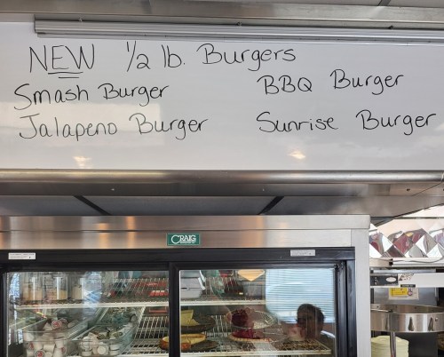 Menu board listing new ½ lb burgers: Smash, BBQ, Jalapeno, and Sunrise Burgers.