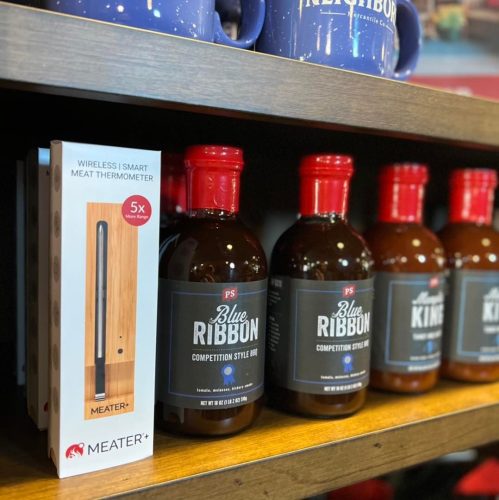 A shelf displaying a wireless meat thermometer and bottles of Blue Ribbon Competition Style BBQ sauce.