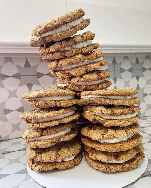 A stack of oatmeal cookies with cream filling, arranged in a pyramid shape on a patterned surface.