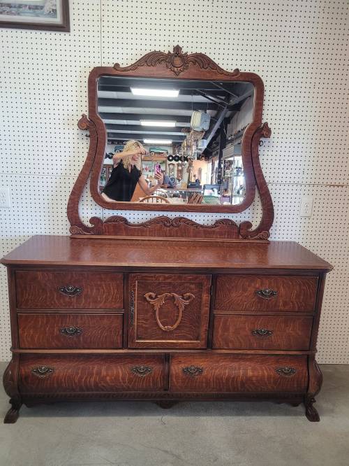 Antique wooden dresser with a large mirror, featuring ornate carvings and multiple drawers.
