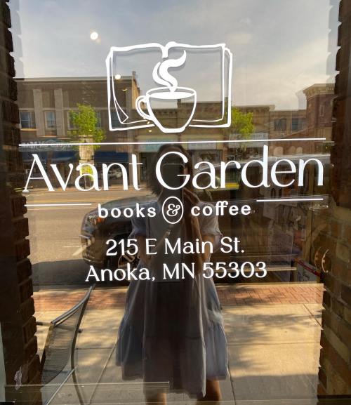 Window display of Avant Garden books & coffee, featuring the address 215 E Main St, Anoka, MN 55303.