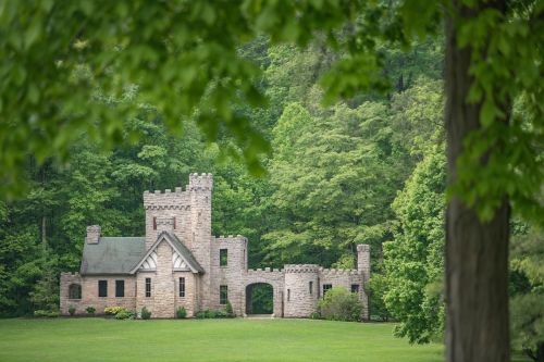 A stone castle surrounded by lush green trees and grass, set in a serene landscape.