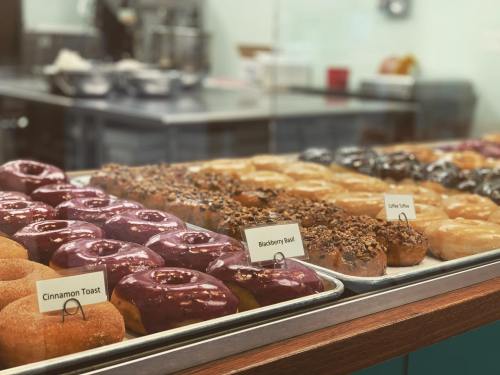 A display case filled with various donuts, including Blackberry Basil, Cinnamon Toast, and Coffee Toffee varieties.