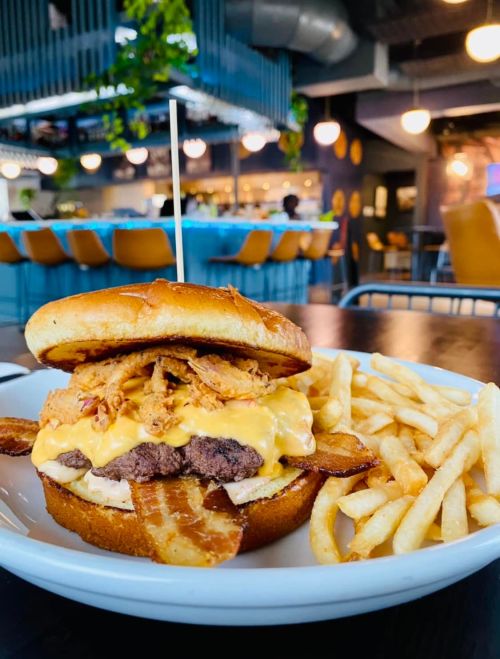 A juicy cheeseburger topped with crispy bacon and fried onions, served with a side of golden French fries.