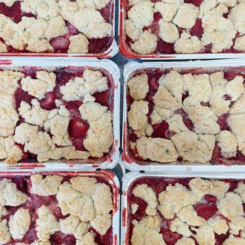 Six trays of freshly baked strawberry cobbler with a golden, crumbly topping.