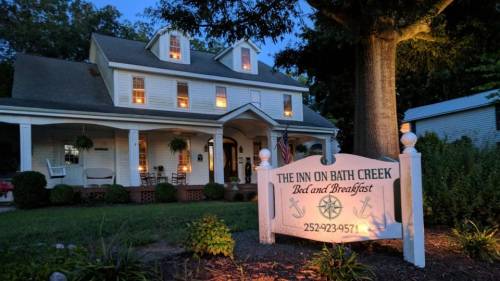 A charming bed and breakfast, "The Inn on Bath Creek," with a welcoming sign and warm lights glowing from the windows.