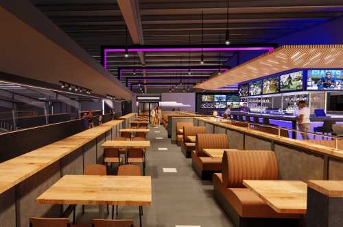 Modern restaurant interior with wooden tables, leather seating, and a bar featuring multiple screens and vibrant lighting.