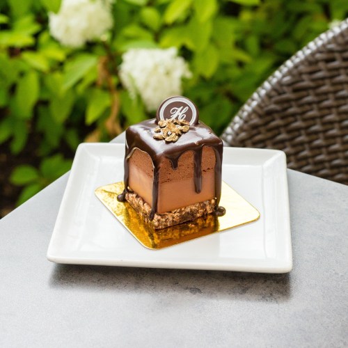 A decadent chocolate dessert on a gold plate, topped with a glossy chocolate glaze and decorative elements.