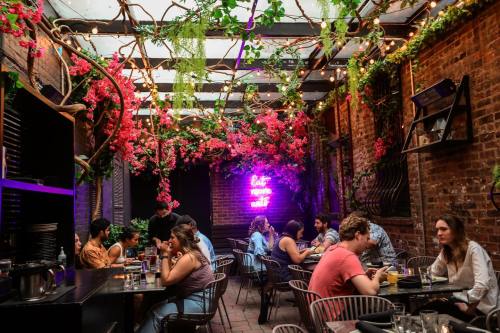 A vibrant restaurant patio adorned with flowers and string lights, featuring diners enjoying their meals.