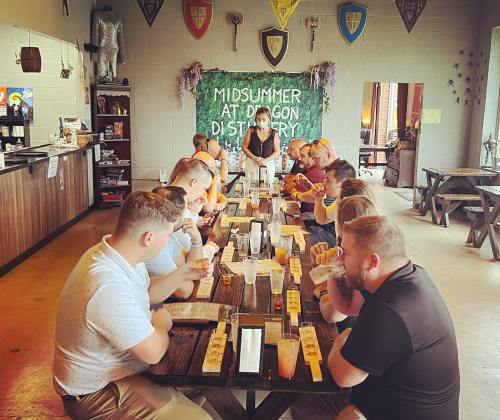 A group of people seated at a long table in a festive setting, enjoying drinks and a meal together.