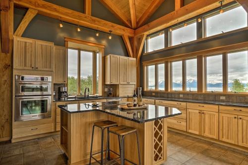 Modern kitchen with wooden cabinetry, large windows, and mountain views, featuring an island and stainless steel appliances.