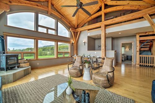 Cozy living area with wooden beams, large windows, and stylish seating, overlooking a scenic outdoor view.
