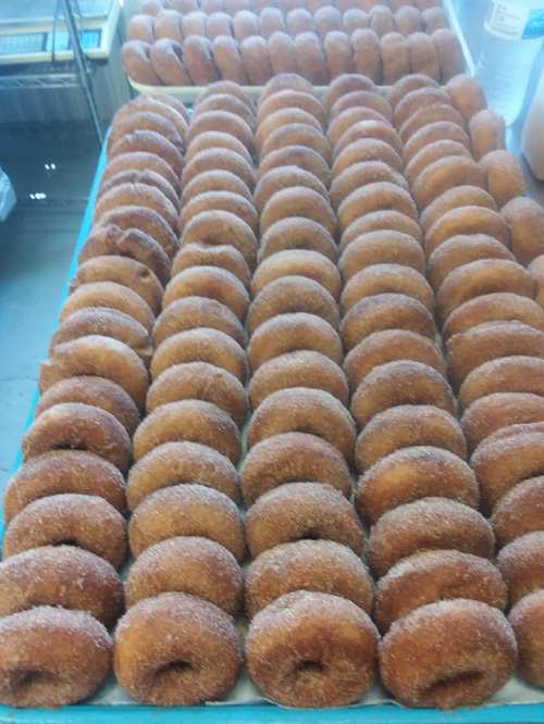 A large tray filled with neatly arranged, golden-brown donuts coated in sugar.