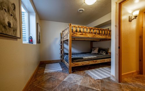 Cozy room featuring a wooden bunk bed, tiled floor, and natural light from a window.