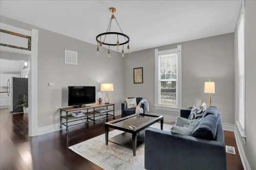 Cozy living room with blue sofas, a coffee table, TV, and warm lighting, featuring a neutral color palette and hardwood floors.