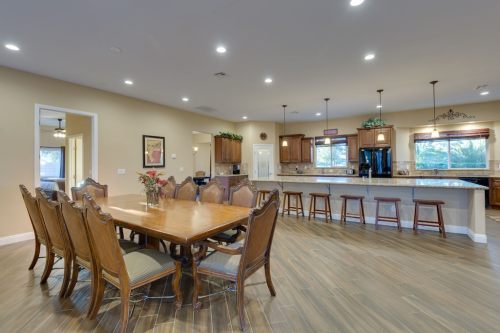 A spacious kitchen and dining area with a large wooden table, bar stools, and modern appliances in warm tones.