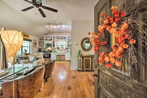 A cozy living space with a wooden door adorned with an orange floral wreath, leading to a bright kitchen area.