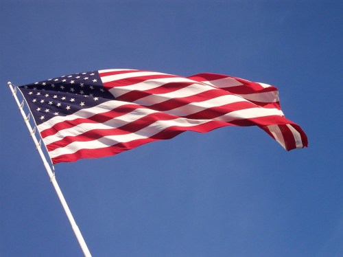 Waving American flag against a clear blue sky.