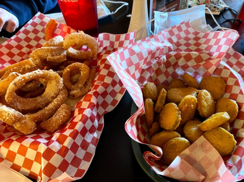 Two baskets of food: one with golden onion rings and the other with crispy, golden nuggets, both in checkered paper.