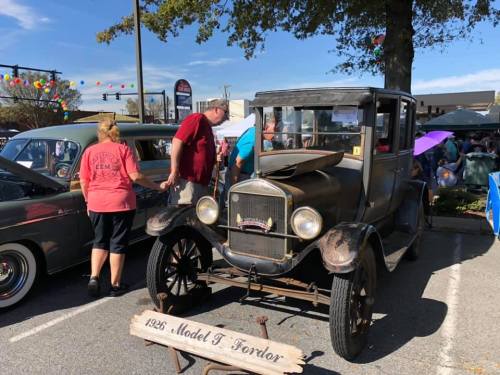 A vintage 1926 Model T Fordor car displayed at a car show, with people admiring it in the background.