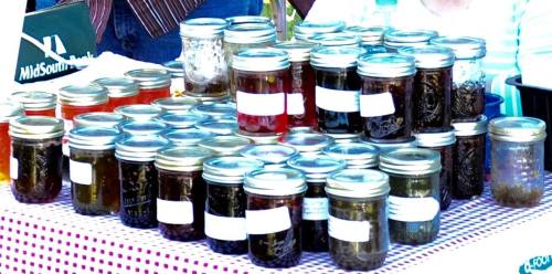 A display of various jars filled with preserves, arranged neatly on a table with a checkered tablecloth.