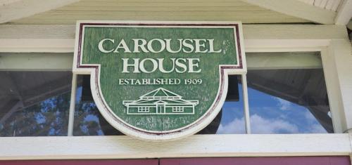 Sign for Carousel House, established in 1909, displayed on a building with a green background and white lettering.