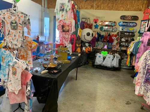 A colorful shop interior featuring clothing, accessories, and skateboards displayed on walls and tables.