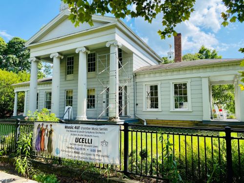 A historic building with columns, featuring a banner for the "Music 4 All" Chamber Music Series and scaffolding.