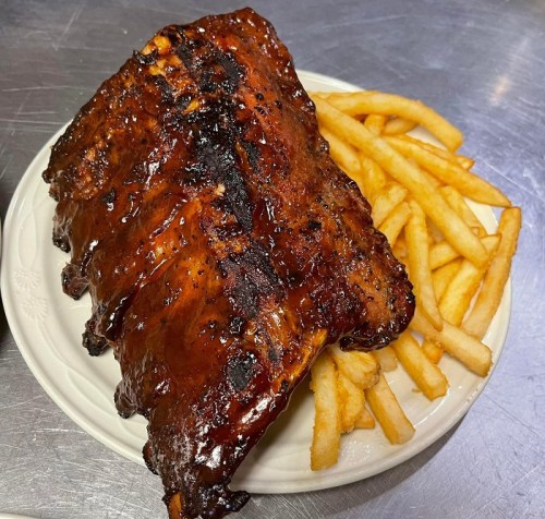 A plate of glazed ribs served with a side of golden French fries.