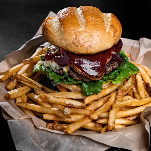 A juicy burger with lettuce, ketchup, and mayonnaise, served with a generous side of crispy French fries.